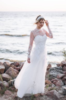denizde kayalık plajda duran çekici sarışın gelin  