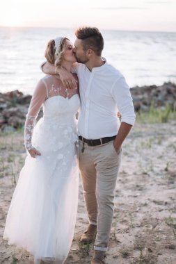 gün batımında sahilde kocası ile öpüşme beyaz elbiseli genç kadın 