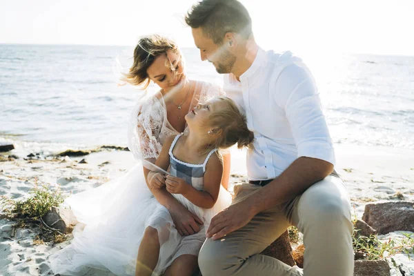 欢快的家庭与女儿一起坐在沙滩上 — 图库照片