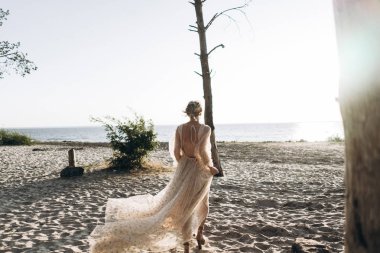 uzun elbiseli genç kadının sahilde yürüyen arka görünümü, tam uzunlukta çekim