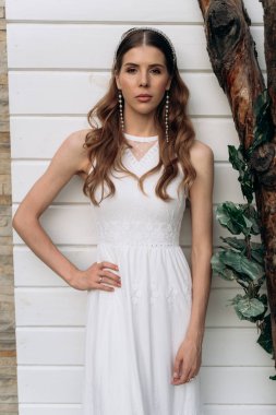 açık havada beyaz ahşap arka plan karşı duran kameraya bakan gelin portresi 