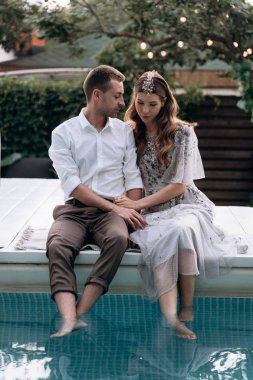 bahçede yüzme havuzunda oturan genç çift
