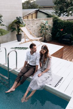 yüzme havuzunda oturan genç adam ve kadının havai görünümü