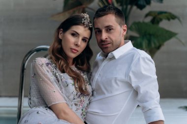 yakışıklı adam ve genç kadın yüzme havuzunda oturan ve kameraya bakarak 