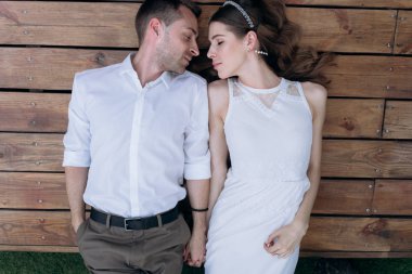 gelin ve damat ahşap plakalar üzerinde yatan ve el ele tutuşarak 