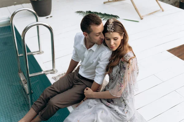 bahçede yüzme havuzunda oturan genç çift