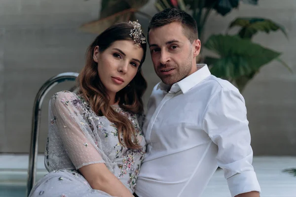 yakışıklı adam ve genç kadın yüzme havuzunda oturan ve kameraya bakarak 