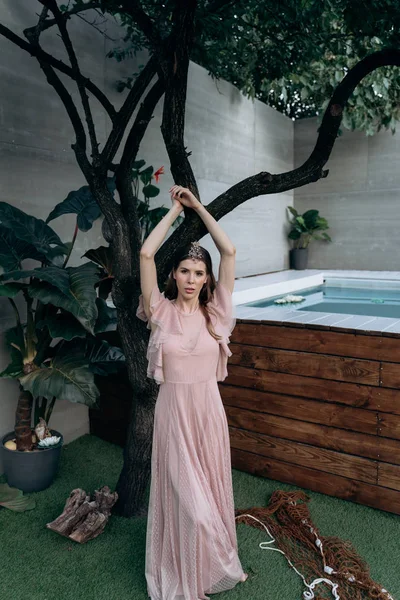 genç kadın arka planda yüzme poool ile bahçede ağaçta poz 