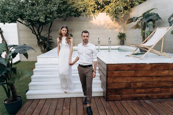 arka planda yüzme havuzu ile bahçede yürüyen şık erkek ve kadın, Tam Uzunlukta atış 