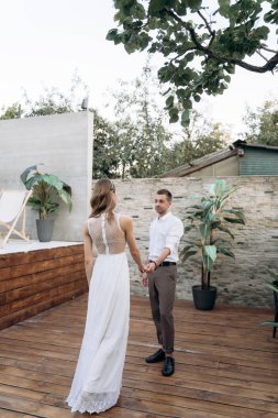 gelin ve damat bahçesinde el ele tutuşarak, Tam Uzunlukta atış 