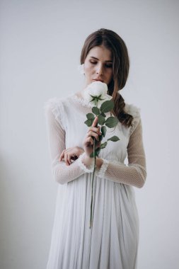 beyaz elbise giyen ve çiçek kokulu açık arka plan üzerinde duran gelin 