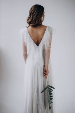 Hafif arka planda kadının arka görünümü ve elinde yaprak tutarak 