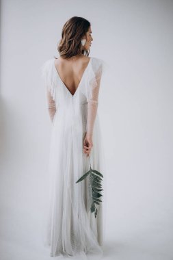 Hafif arka planda kadının arka görünümü ve elinde yaprak tutarak 