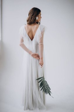 Hafif arka planda kadının arka görünümü ve elinde yaprak tutarak 