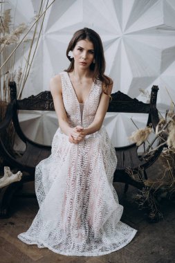 ahşap bankta oturan boho tarzıbeyaz elbise giyen çekici model 