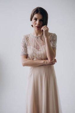 açık arka planda kameraya bakarak boho tarzıbej elbise giyen gelin 