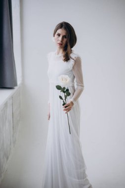 kadın ışık arka plan üzerinde kameraya bakıyor ve elinde gül çiçek tutarak 