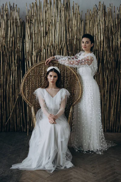 Mujeres Jóvenesen Vestidos Blancos Sentados Una Silla Grande Mirando Cámara — Foto de Stock