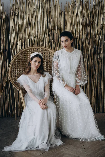 Mujeres Jóvenesen Vestidos Blancos Sentados Una Silla Grande Mirando Cámara —  Fotos de Stock