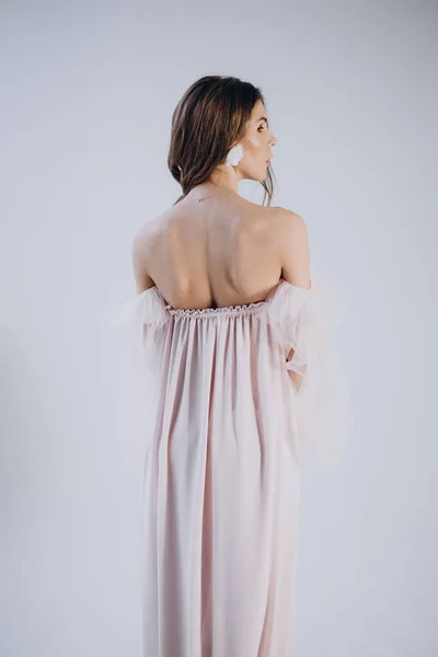 back view  of woman wearing dress in boho style  standing on light background