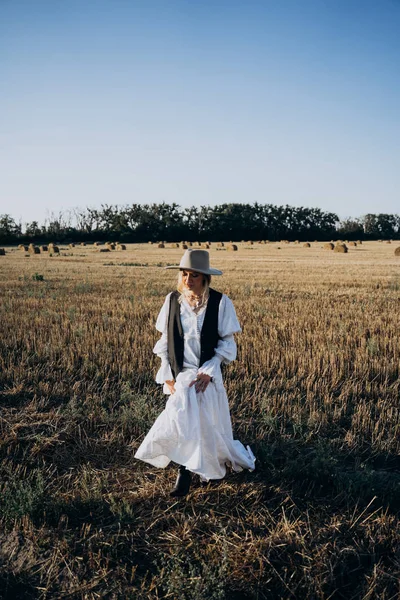 前看农业年轻女子在长白色礼服走在田野上白天的时间 — 图库照片