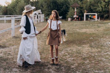 anne ve kızı birlikte çiftlikte yürürken el ele tutuşuyor 