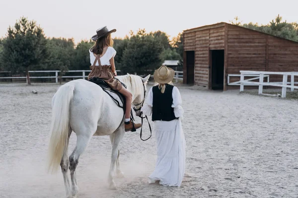 Visão Traseira Menina Equitação Cavalo Enquanto Mãe Segurando Freio Andando — Fotografia de Stock