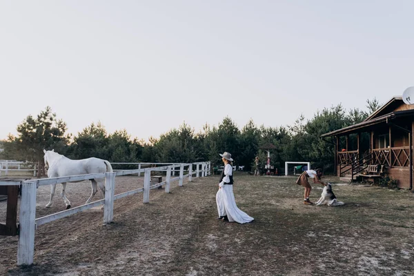 woman in long dress with daughter spending time together on the ranch