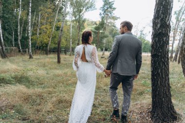 arka görünüm Birch Grove el ele tutuşan yakışıklı adam ile beyaz elbisegüzel hamile kadın         