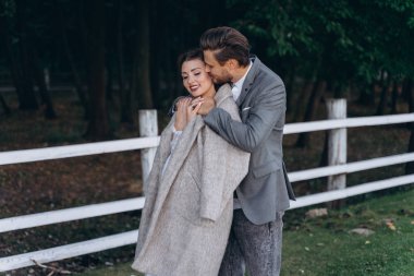 adam shes geri yolun yanında duran hamile bir kadın sarılma, shes omuzlarında bir ceket ile bir kadın