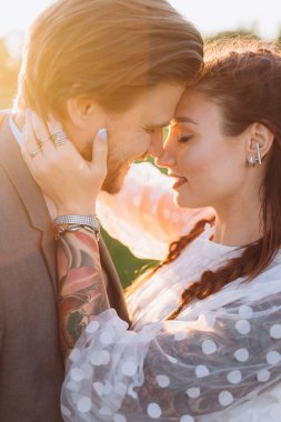 güzel kadın ve yakışıklı adam batan güneşe karşı yüz yüze duruyor