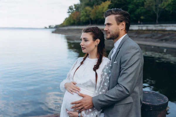 夫妇拥抱肚的孕妇对湖 — 图库照片