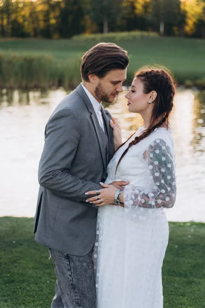 美丽的孕妇和英俊的男人站在绿色草坪上面对面 — 图库照片