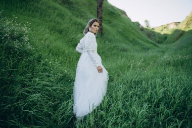 Yeşil bölgede duran beyaz elbiseli çekici kadın.