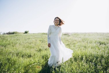 Tarlada yürüyen uzun beyaz elbiseli çekici bir kadın. 