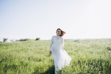 Tarlada poz veren uzun beyaz elbiseli güzel bir kadın. 