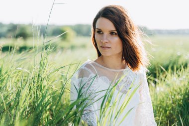 Beyaz elbiseli bir kadının portresi tarlada oturuyor. 