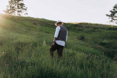 Parkta yürüyen şapkalı yakışıklı adam.