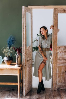 Modern iç mekanda poz veren dövmeli çekici bir kadın.