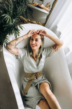 Genç bayan boş bir küvette yatıyor, tepeden bakıyor. 