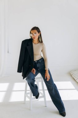 Çekici kız siyah ceketli sandalyede oturuyor. 