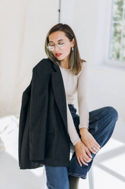  Ceketli şık bir kızın portresi sandalyede oturuyor. 