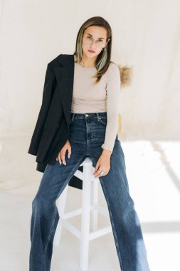 Sandalyede otururken ceketli bir kadın model. 