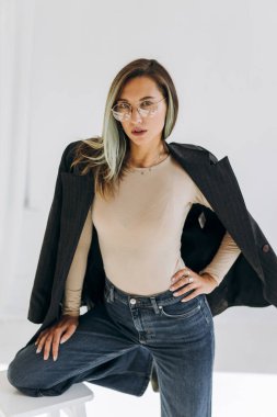 Sandalyede otururken ceketli bir kadın model. 