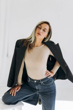 Sandalyede otururken ceketli bir kadın model. 