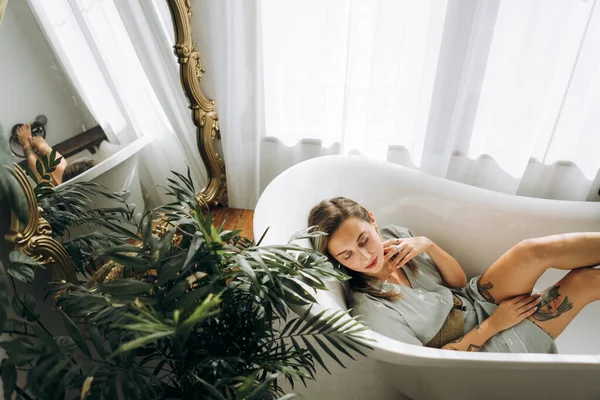 Genç bayan boş bir küvette yatıyor, tepeden bakıyor. 