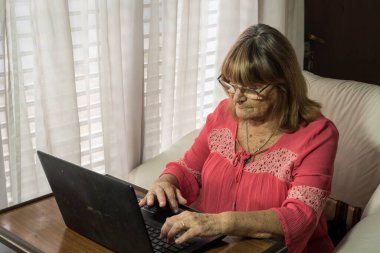 Daha yaşlı bir kadın sosyal uzaklıkla buluşurken iletişim kurmak için modern teknolojileri kullanıyor.