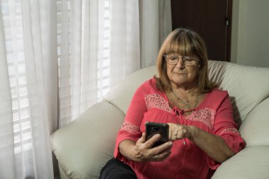 Daha yaşlı bir kadın sosyal uzaklıkla buluşurken iletişim kurmak için modern teknolojileri kullanıyor.