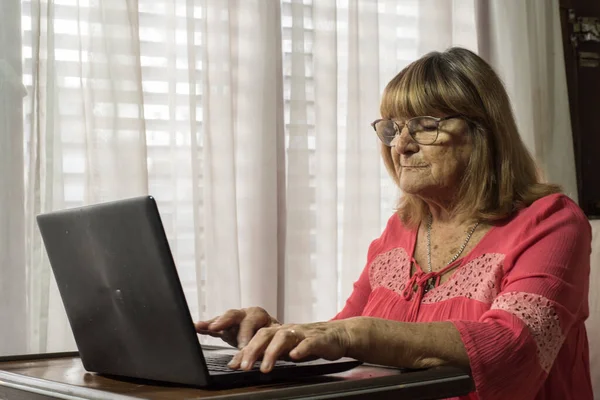 older woman using modern technologies on her devices to communicate while meeting social distancing