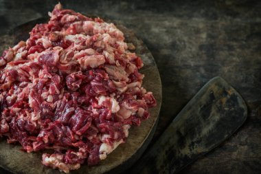 Parçalanmış ham sığır eti kesme tahtası üzerinde bıçak ile.